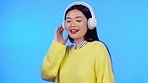 Asian woman, headphones and listen to music, dance and fun with entertainment on blue background. Fun, radio and streaming with mockup space, young gen z female in studio with fashion and lifestyle