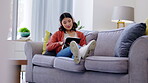 Tablet, headphones and woman relax on couch with music streaming app, social media and watching videos at home. Gen z asian person or young Korea girl on sofa, digital tech and listening to audio