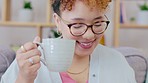 Black woman, reading and drinking coffee on a living room sofa feeling relax and calm at home. Lounge, house and smile of a young person on a couch resting with books happiness in the morning