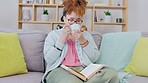 Black girl, reading and tea drinking on living room sofa feeling relax and calm at home. Lounge, house and book read of a young person on a couch resting with books and university textbook in morning