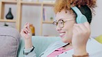 Black woman, music headphones and dance on sofa with smile, happiness and relax in home living room. Gen z girl, streaming and audio electronics for radio, dancing and happy for song on internet app