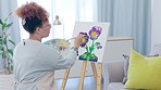 Creative, art and woman painting in her living room for hobby, self expression or small business. Creativity, artist and female painter working with paint on a canvas to create a picture at her home.