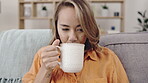 Woman, thinking and home drinking coffee with a tablet for reading on living room sofa to relax. Asian model person on lounge couch with cup of tea to think about internet and house wifi connection