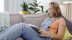 Woman, reading and book on home sofa to relax or learning, studying and hobby in free time. Asian model person read books on lounge couch for knowledge, peace and calm with glasses for vision