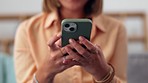 Woman, hands and phone on sofa for social media, chatting or texting in living room at home. Closeup of female hand typing on smartphone for chat, browsing or mobile app on the lounge couch indoors