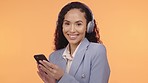 Headphones, phone and woman face isolated on orange background for music streaming app and listening to audio. Young black person with cellphone, electronics or headphone sound technology in studio