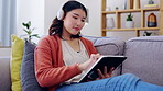 Tablet, headphones and asian woman on couch with music streaming app, online games and creative e learning at home. Gen z person or young Korea girl relax on sofa, digital tech and listening to audio