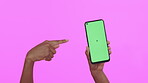 Person, hand pointing at phone and green screen, mockup space and advertising isolated on pink background. Display, marketing and product placement with technology promo, communication and mobile app