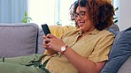 Phone, laughing and black woman on a sofa for social media, texting or funny meme in her home. Online, comic and girl relax with smartphone on couch, chatting or reading post or update in living room