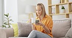 Coffee, phone and woman relax on a sofa with social media, browsing and reading in her home. Tea, app and smartphone for asian girl in a living room, chilling and happy on day off or weekend indoors