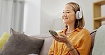 Dance, music and search for woman with headphones and phone for streaming, playlist or song on sofa. Radio, dancing and asian girl chilling, happy and and smile in living room with podcast selection