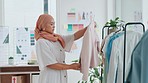 Fashion, retail and muslim woman with clothing in store, checking stock and design quality of product. Small business, startup and young islamic designer in hijab clothes on rail and inventory check.