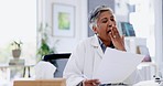 Yawn, tired and senior doctor with documents at desk with fatigue, sleepy and exhausted in hospital. Healthcare, clinic and bored woman medical worker reading paperwork, prescription or insurance