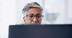 Serious, business woman reading on computer email, market research or report analysis, review and data analytics in office. Planning, data management of senior boss, or female in glasses on laptop pc