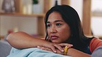 Depression, sad and woman on a sofa with mental health problems thinking in her living room. Pensive, unhappy and upset Asian female sitting and contemplating emotions in her apartment or home.