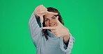 Woman, hands and frame for face on green screen or chroma key background for photo capture. Hand of female portrait framing facial expression through fingers against a studio chromakey backdrop