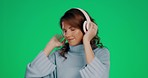 Woman, dancing and headphones listening to music with smile against a green studio background. Happy female with headset enjoying a dance to audio track, streaming or fun entertainment on mockup