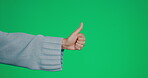 Hand, thumbs up and approval on a green screen background in studio to gesture yes in agreement. Emoji, thank you and motivation with a woman gesturing for positive review on black mock up space