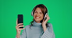 Woman, phone and headphones listening to music dancing with smile against a green studio background. Happy female with headset and smartphone enjoying audio track streaming or entertainment on mockup