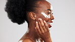 Face, skincare and water splash of happy black woman in studio isolated on a gray background. Cleaning portrait, cosmetics bubbles and laughing female model apply lotion, cream or skin moisturizer.