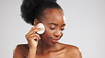 Face, skincare and black woman with cotton in studio isolated on a gray background. Dermatology, eyes closed and female model with facial pad to remove makeup cosmetics for healthy skin and cleaning.