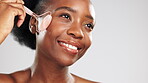 Face, massage and gua sha roller with a black woman in studio on a gray background for natural skincare. Facial, relax and antiaging with an attractive young female massaging her skin for beauty