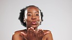 Face, skincare and black woman blowing kiss in studio isolated on a gray background. Portrait, makeup cosmetics and laughing female model blow air kisses for self love, romantic smile and beauty.