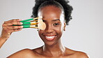 Face makeup, smile and black woman with brushes in studio isolated on a gray background. Portrait, cosmetics and laughing female model with product or tools to apply foundation or powder for beauty.