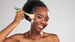 Face, makeup and happy black woman with brush in studio isolated on a gray background. Skincare smile, cosmetics or laughing female model with product or tool to apply foundation or powder for beauty