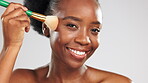 Makeup, face and happy black woman with brush in studio isolated on a gray background. Skincare smile, cosmetics or laughing female model with product or tool to apply foundation or powder for beauty