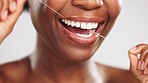 Face, hands and black woman flossing teeth in studio isolated on a gray background. Tooth care, oral health and happy female model with floss for dental cleaning, personal hygiene and gum wellness.