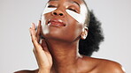 Skincare, face and black woman with eye patches in studio isolated on a gray background. Dermatology portrait, beauty cosmetics and happy female model with facial collagen mask for healthy skin.