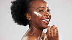 Face, skincare and happy black woman with cream in studio isolated on a gray background. Dermatology portrait, cosmetics and laughing female model apply lotion, creme or moisturizer for healthy skin.