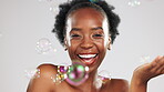 Face, skincare and laughing black woman with bubbles in studio isolated on gray background. Dermatology portrait, makeup cosmetics and happy female model with bubble for cleaning, hygiene or wellness