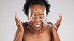 Face, skincare and laughing black woman with water splash  in studio isolated on a gray background. Cleaning, hygiene and happy female model bathing or washing for facial wellness and healthy skin.