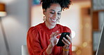 Happy black woman, night business and typing with cellphone at computer, office desk and online app. Female smile, overtime worker and smartphone for notification, social media and network connection