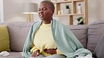 Black woman, sofa and stomach with cramps, pain and rubbing for healthcare in home living room. Gen z african girl,  digestion and menstruation on couch for health, medical or constipation in house