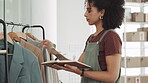 Woman, fashion designer and writing in notebook checking stock of clothing line at boutique store. Female small business owner doing inspection on garment, items or clothes on rack in retail workshop