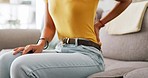 Closeup, black woman on couch and back pain with stress, muscle tension and accident on living room. Zoom, female and lady on sofa with strain, anxiety and injury in lounge, overworked and exhausted