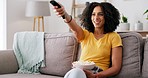 Black woman, remote control and popcorn in home living room with smile, funny movie or relax with eating. Gen z, girl and watching tv with streaming, comedy film and hungry for snack on lounge couch