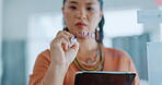 Asian woman, writing and tablet in planning schedule on glass board for tasks, ideas or reminder at office. Serious female in project plan, sticky note or idea for priority, marketing or advertising