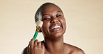 Cosmetics, beauty and black woman with a brush in studio for a makeup, natural and face routine. Beautiful, happy and portrait of African model doing cosmetology facial treatment by brown background.