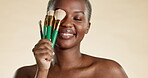 Beauty, makeup and brush with black woman in studio for cosmetics, foundation and blush. Self care, glow and product with girl model and tools for powder, facial and treatment isolated on background