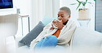 Coffee, relax and black woman on sofa in home living room drinking caffeine, espresso or cappuccino. Tea, thinking and African female relaxing on couch in lounge with beverage and blanket in house.