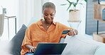 Laptop, online shopping and retail with a black woman customer holding a credit card in her home. Computer, payment and banking with a female consumer using the internet to search an ecommerce sale