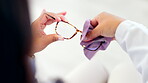 Hands, glasses and cleaning with an optician woman at work in her optometry office closeup from above. Eyewear, fabric and vision with an eye care doctor in a clinic to wipe prescription frame lenses