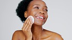 Skincare, beauty and black woman with cotton pad on face, smile and makeup or dirt removal with luxury skin product. Dermatology, cosmetics and facial for happy model isolated on grey background.