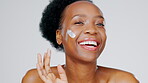 Black woman, face and cream, beauty and laughing, healthy skin and portrait with moisturizer isolated on studio background. Happy female, sunscreen and skincare lotion, cosmetic product and glow