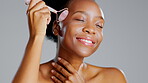 Rose quartz, black woman and face roller massage of a model with beauty facial treatment. Isolated, gray background and studio with a dermatology, skin glow and cosmetics stone tool with a smile