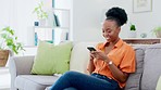 Phone, happy and black woman on a sofa typing a text message while relaxing in the living room. Happiness, communication and African female networking on social media or the internet with a cellphone